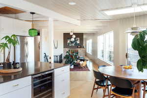 Kitchen with pendant lighting, white cabinetry, stainless steel fridge, and beverage cooler