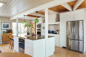 Kitchen featuring white cabinetry, stainless steel appliances, and hanging light fixtures