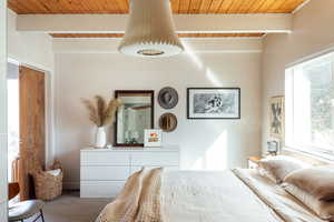 Carpeted bedroom featuring beam ceiling and wooden ceiling