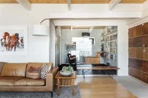 Living room with wood-type flooring and beam ceiling