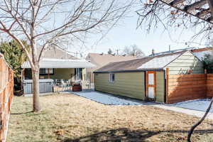 Rear view of house featuring a hot tub, a patio, and a lawn