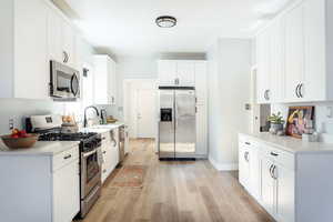 Kitchen featuring sink, light hardwood / wood-style flooring, white cabinets, and appliances with stainless steel finishes