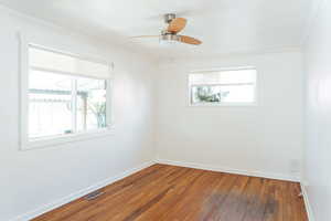 Empty room featuring dark hardwood / wood-style flooring, a wealth of natural light, ornamental molding, and ceiling fan