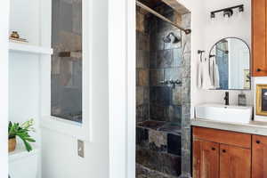 Bathroom featuring vanity, tiled shower, and toilet