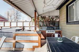 Wooden terrace featuring an outdoor kitchen and a grill