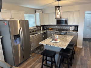 Kitchen featuring gray cabinets, a kitchen island, pendant lighting, sink, and stainless steel appliances