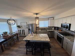 Kitchen with pendant lighting, appliances with stainless steel finishes, a center island, and white cabinets