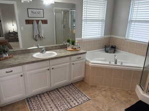 Bathroom with shower with separate bathtub, plenty of natural light, and vanity