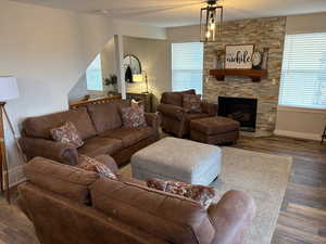 Living room with a stone fireplace and dark wood-type flooring