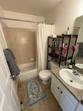 Full bathroom featuring shower / tub combo with curtain, vanity, toilet, and tile patterned flooring