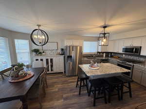 Kitchen with pendant lighting, light stone counters, stainless steel appliances, and a kitchen island