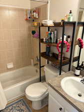 Full bathroom featuring shower / tub combo with curtain, tile patterned floors, toilet, and vanity