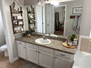 Bathroom featuring vanity, a washtub, and toilet