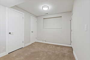 Empty room featuring light carpet and a textured ceiling