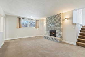 Unfurnished living room with light colored carpet, a brick fireplace, and a textured ceiling