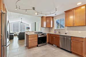 Kitchen featuring lofted ceiling, sink, hanging light fixtures, stainless steel appliances, and backsplash