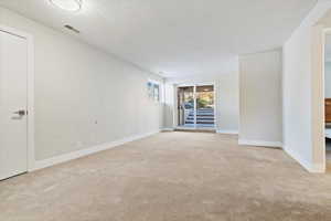 Carpeted empty room featuring a textured ceiling