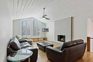 Living room featuring wood ceiling, a fireplace, light hardwood / wood-style floors, and vaulted ceiling