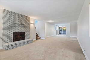 Unfurnished living room with a fireplace, light colored carpet, and a textured ceiling