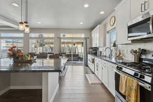 Kitchen with dark stone countertops, appliances with stainless steel finishes, and white cabinets