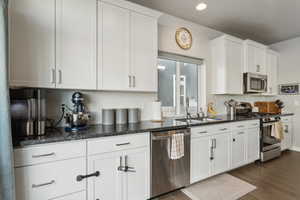 Kitchen with dark hardwood / wood-style flooring, sink, stainless steel appliances, and white cabinets