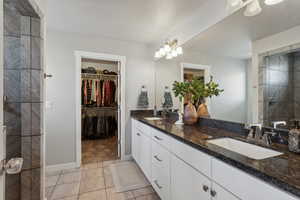 Bathroom with vanity, tile patterned flooring, and a tile shower