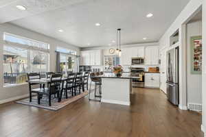 Kitchen featuring white cabinetry, hanging light fixtures, a kitchen island, and appliances with stainless steel finishes