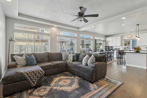 Living room with wood-type flooring, sink, ceiling fan, and a textured ceiling