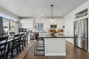 Kitchen featuring sink, hanging light fixtures, stainless steel appliances, white cabinets, and a kitchen island