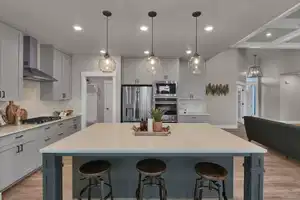 Kitchen with appliances with stainless steel finishes, decorative light fixtures, a breakfast bar area, wall chimney range hood, and a spacious island