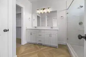 Bathroom featuring tile patterned flooring, vanity, and tiled shower