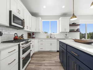 Kitchen with white cabinetry, sink, white appliances, and blue cabinetry