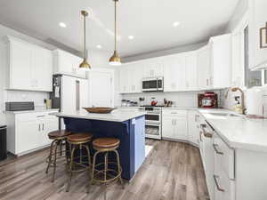 Kitchen with double oven range, a center island, sink, and white cabinets