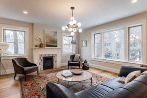 Living room featuring a notable chandelier, a fireplace, and light hardwood / wood-style floors