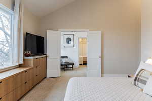 Carpeted bedroom featuring high vaulted ceiling