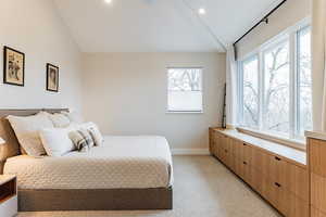 Carpeted bedroom featuring lofted ceiling