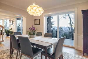 Dining area with a mountain view, crown molding, light hardwood / wood-style floors, and a chandelier