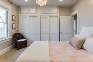 Bedroom featuring multiple windows, a notable chandelier, and a closet