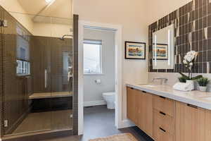 Bathroom with walk in shower, tile patterned floors, vanity, and toilet