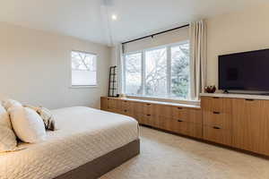 Carpeted bedroom with multiple windows and vaulted ceiling