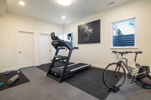 Workout room with dark carpet and a healthy amount of sunlight