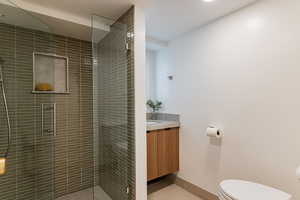 Bathroom with tile patterned floors, vanity, toilet, and a shower with shower door