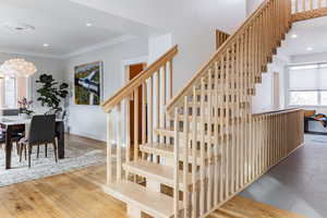 Staircase with crown molding and hardwood / wood-style floors