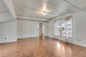 Unfurnished room with beam ceiling and hardwood / wood-style flooring