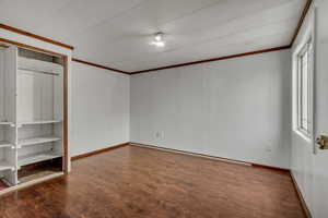 Unfurnished bedroom with ornamental molding and dark hardwood / wood-style flooring