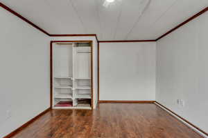 Unfurnished bedroom with a closet, ornamental molding, and dark hardwood / wood-style floors