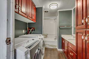 Washroom featuring washer and dryer, sink, and dark hardwood / wood-style flooring