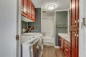 Clothes washing area featuring washer and dryer, sink, and dark hardwood / wood-style flooring