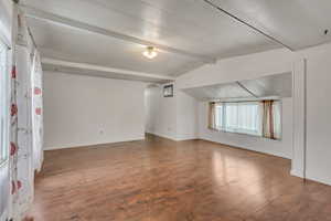 Bonus room with vaulted ceiling with beams and dark hardwood / wood-style floors