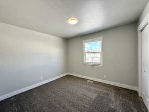 Spare room featuring a textured ceiling and dark colored carpet